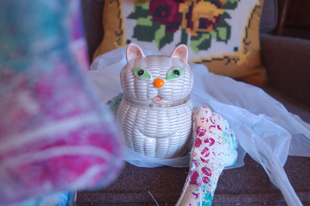 Whimsical cat doll poses with ceramic cat piggy bank.