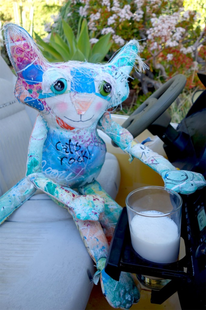 The Chairman cat doll poses with a glass of milk in a cuplholder in his car.