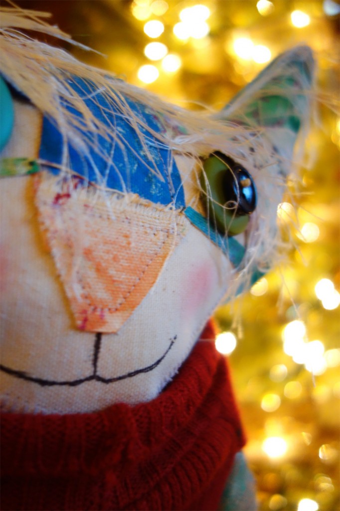 The Chairman cat doll is posed in front of the Christmas tree.