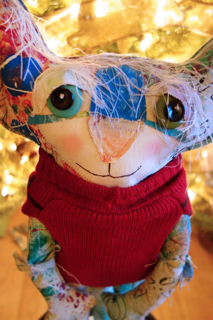 The Chairman, cute cat doll, posed in a dog sweater in front of the Christmas tree.