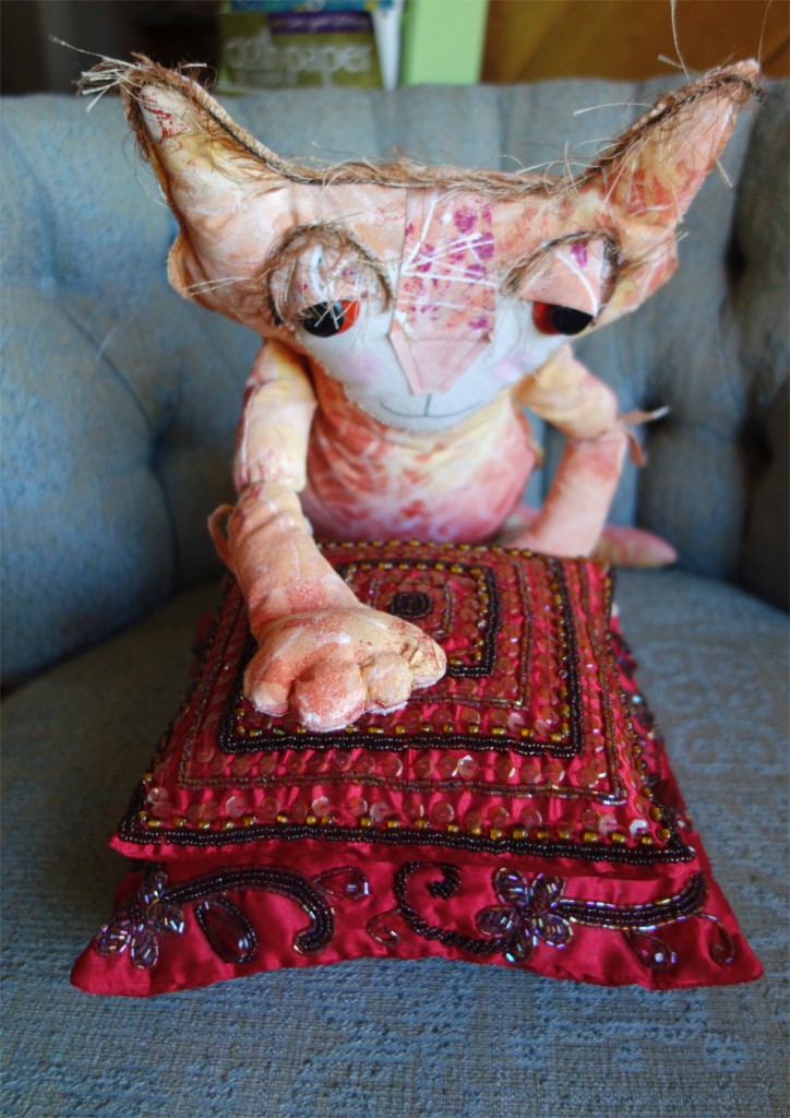 Ginger has her paw on two beautiful little red pillows stacked on top of each other. They are embellished with jewels and sequins.