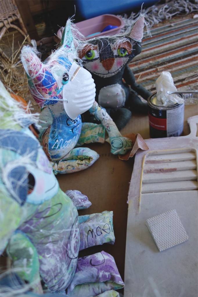 Three cute cat dolls, including the Chairman and CEO, are applying bondo to the hood of the car.