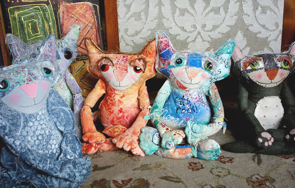 A row of cute, colorful cat dolls sits crossed legged as they meditate.
