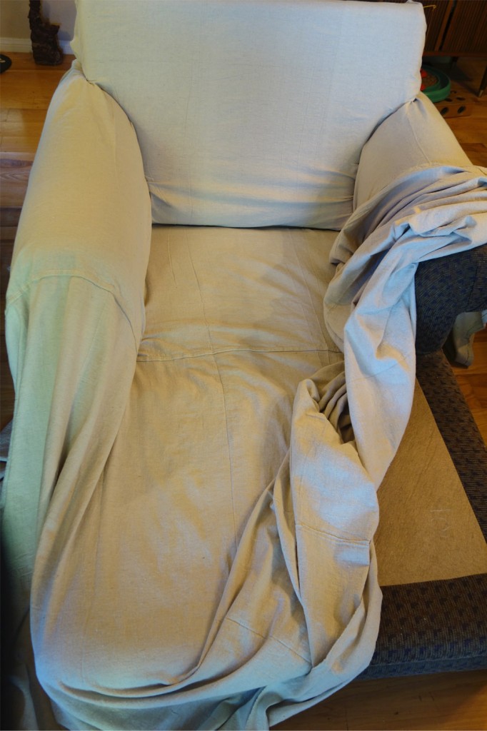 A very large chaise with drop cloth partially draped over it.
