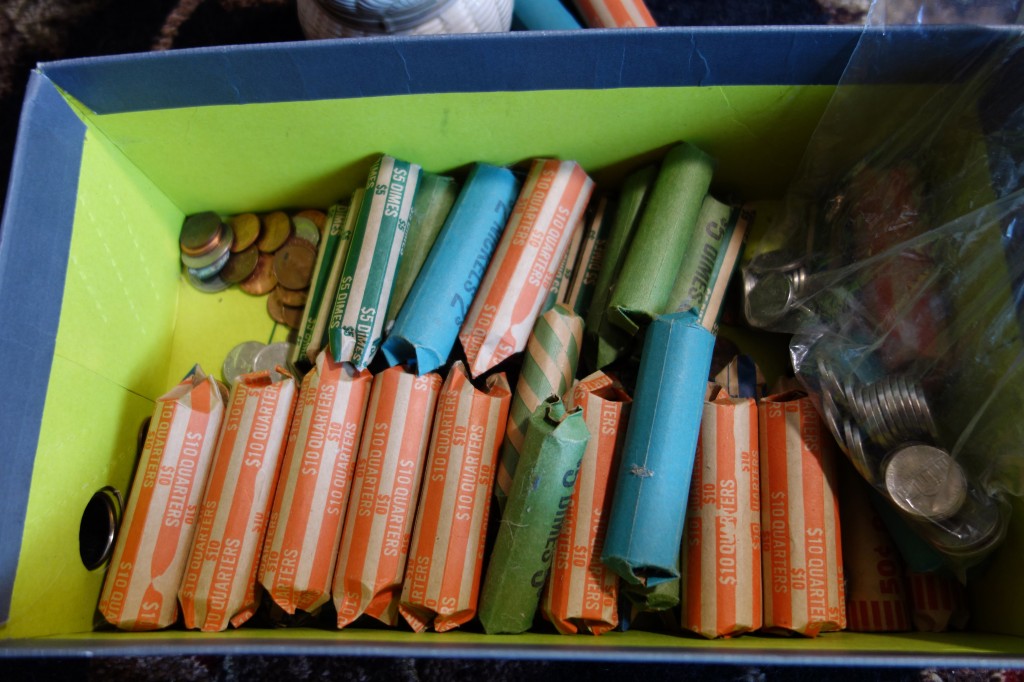 A shoebox full or coins rolled in wrappers ready to go to the bank. There are a lot of rolls!