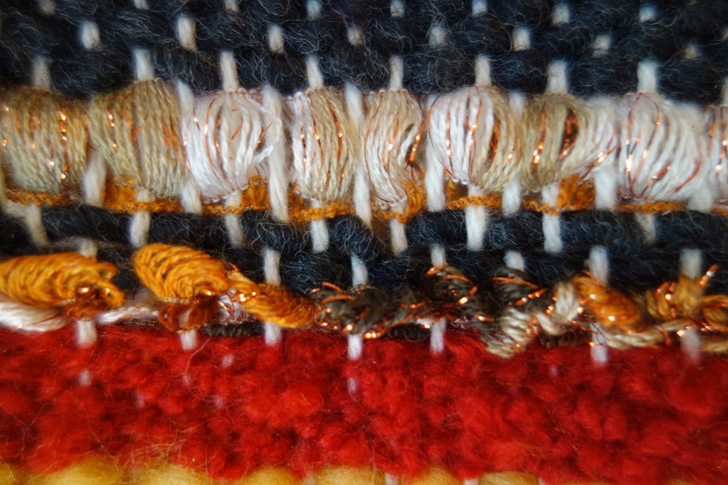 Closeup of colorful yarns and ribbons woven together.