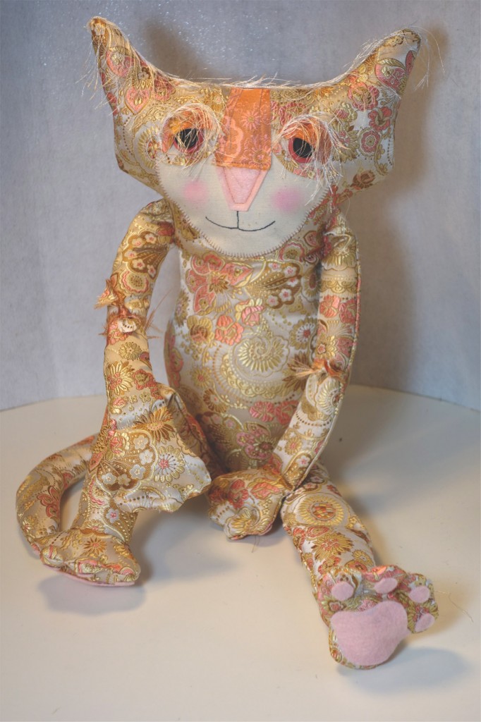A very adorable cat doll made out of Asian silk brocade fabric. She sits with a sultry look on her face.
