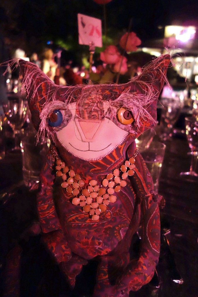 Eve is sitting on the dinner table with roses, candlelight and wine glasses in the background.