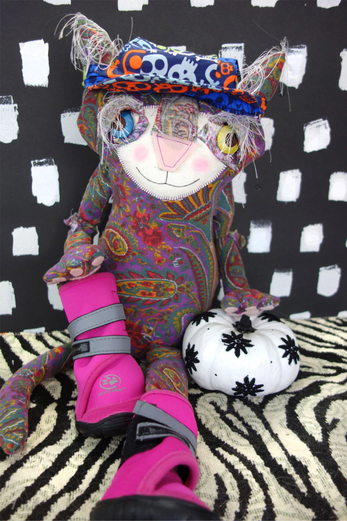Eve 2.0 Cat doll is wearing a cap with colorul skulls on it. She is wearing pink boots meant for dog paws.