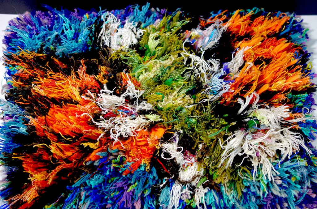 Very colorful small rug made out of long chunks of yard. A very wild shag rug.