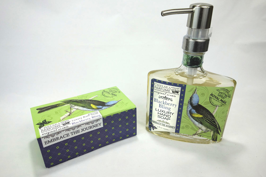 A bar soap box with a beautiful bird and a matching glass bottle of liquid hand soap.