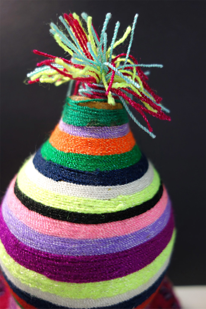 A colorful pom-pom sits on top of the gourd.