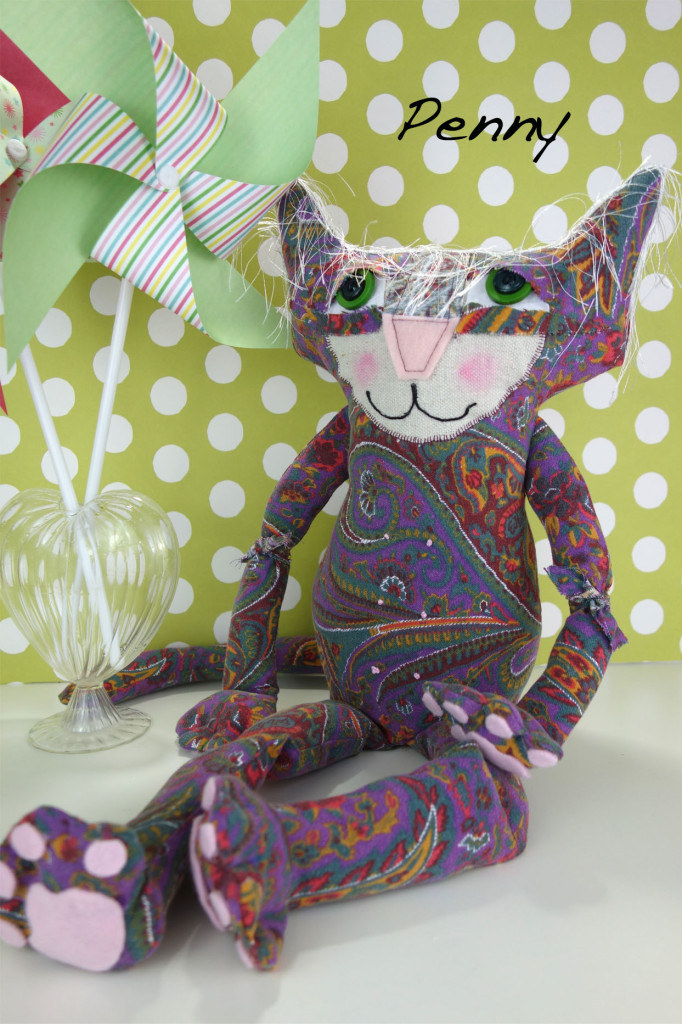 Adorable soft sculpture cat doll made out of vintage 1960's fabric. She sits in front of a green and white polka dot background and has two colorful pinwheels next to her.