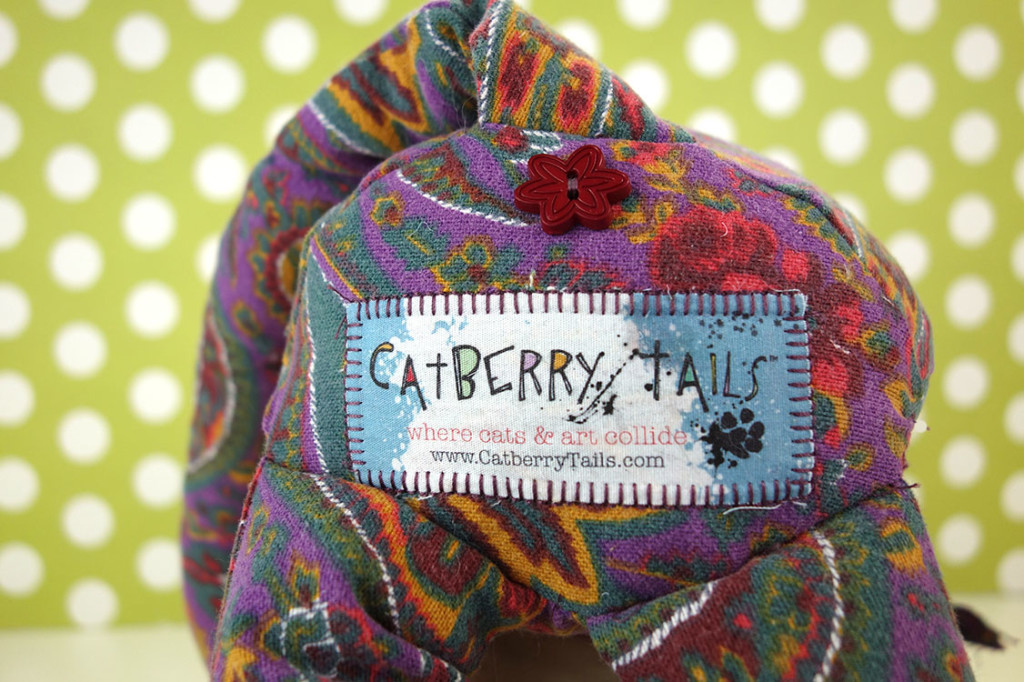 A butt shot showing the floral button under the tail and the official Catberry Tais tag.
