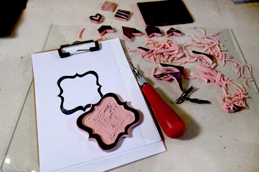 A photo of rubber stamp carving tools and some stamps that have been carved.