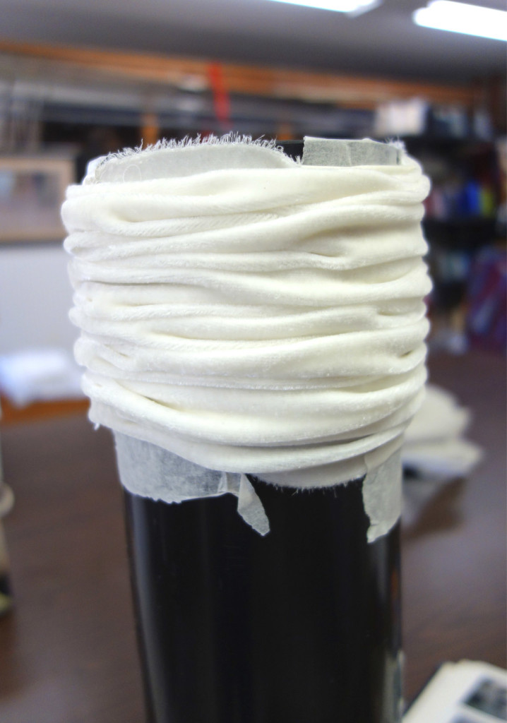Silk velvet fabric wrapped and scrunched on a large pole in preparation for Shibori method of dying fabric.
