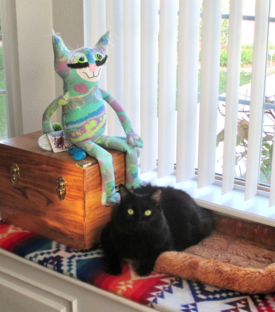 Soft sculpture cat sits with a real life black cat.