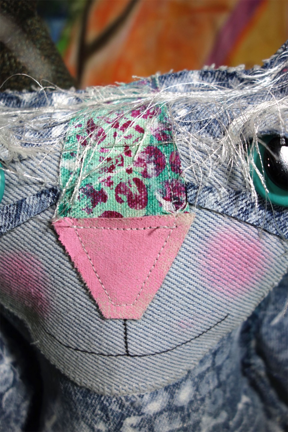 Closeup of a denim cat dolls adorable face made from hand painted demin fabric.